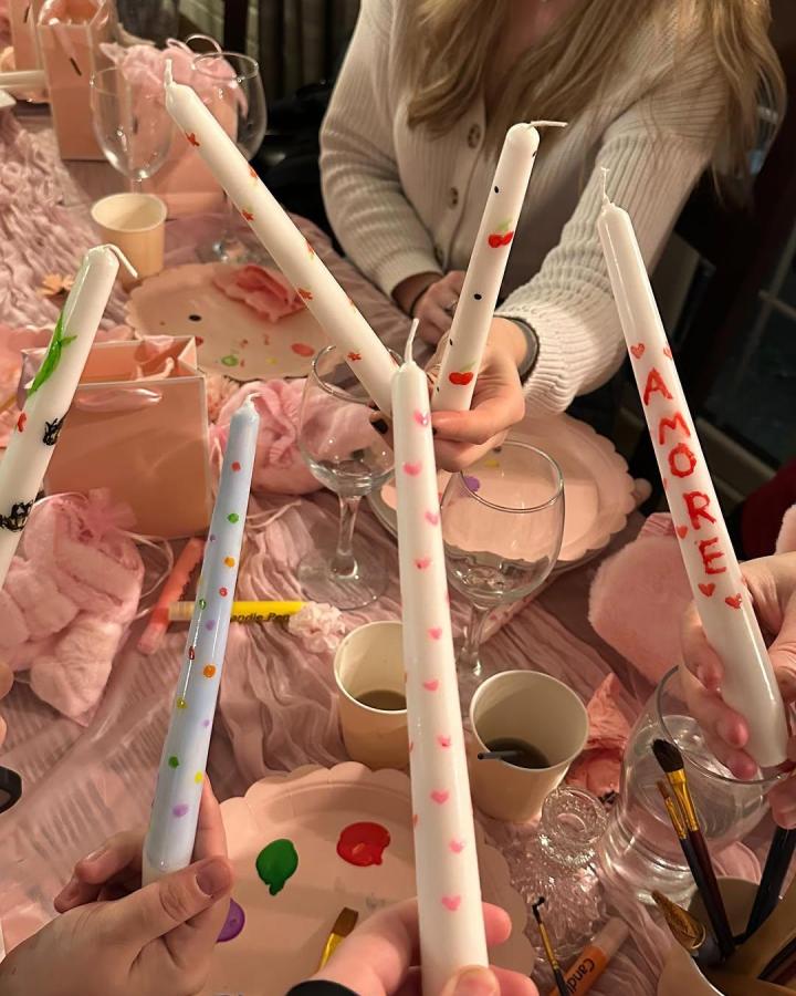 White candles hand-painted with hearts and words at a pink-themed craft night from @surreygirlssocials showing personalized candle craft night themes for adults.