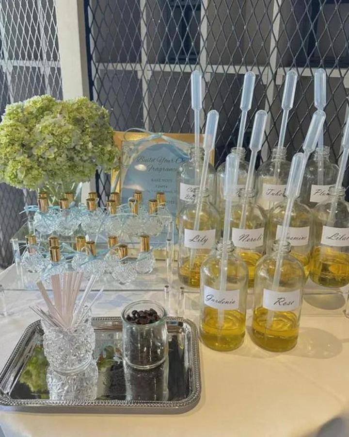 Clear vintage glass bottles with golden caps and pipettes for a perfume bar craft night themes for adults. Elegant setup from Pretty Party Boxx.