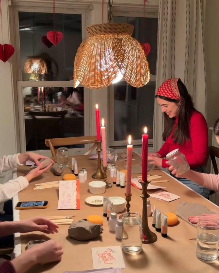 Natural-colored woven lampshade over a craft table with clay and candles from @emiliamariehome. Cozy craft night themes for adults with warm lighting and heart decor.