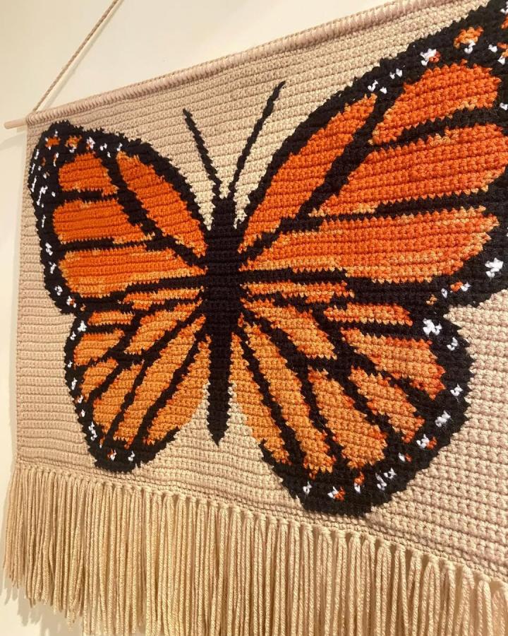 Orange black and cream crochet wall hanging with monarch butterfly and fringe from @crochetedbylarissa. Detailed and cozy craft idea.