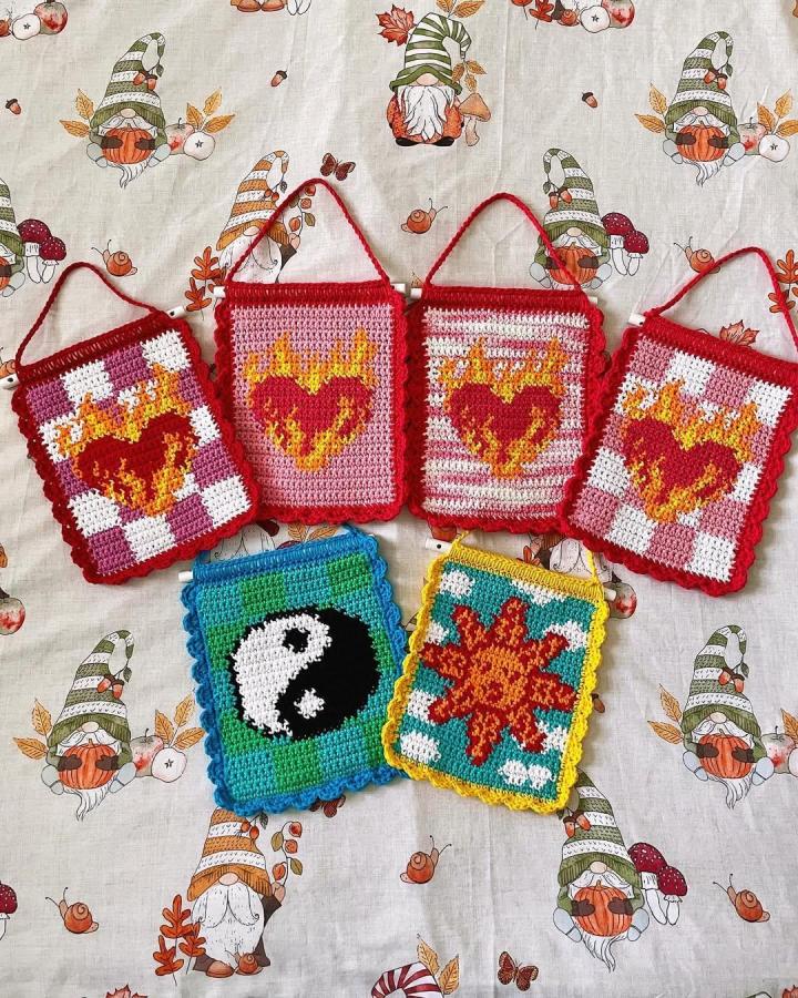 Fiery red and orange heart crochet wall hangings with scalloped edges from @crochetbyreanne on autumn-themed fabric background.