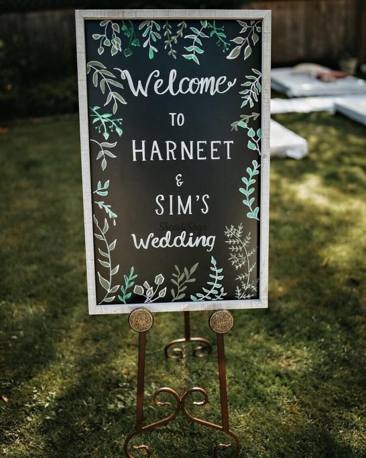 Black chalkboard welcome sign with botanical green and white artwork on metal stand diy wedding welcome sign ideas from Wedding Bazaar. Rustic outdoor wedding décor.
