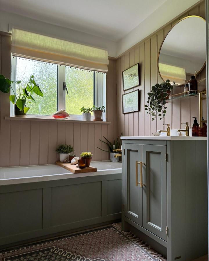 sage green bathroom cabinetry and brass details in cozy bath from @theoldcroftcottage with natural plants and wood elements green bathroom decor ideas
