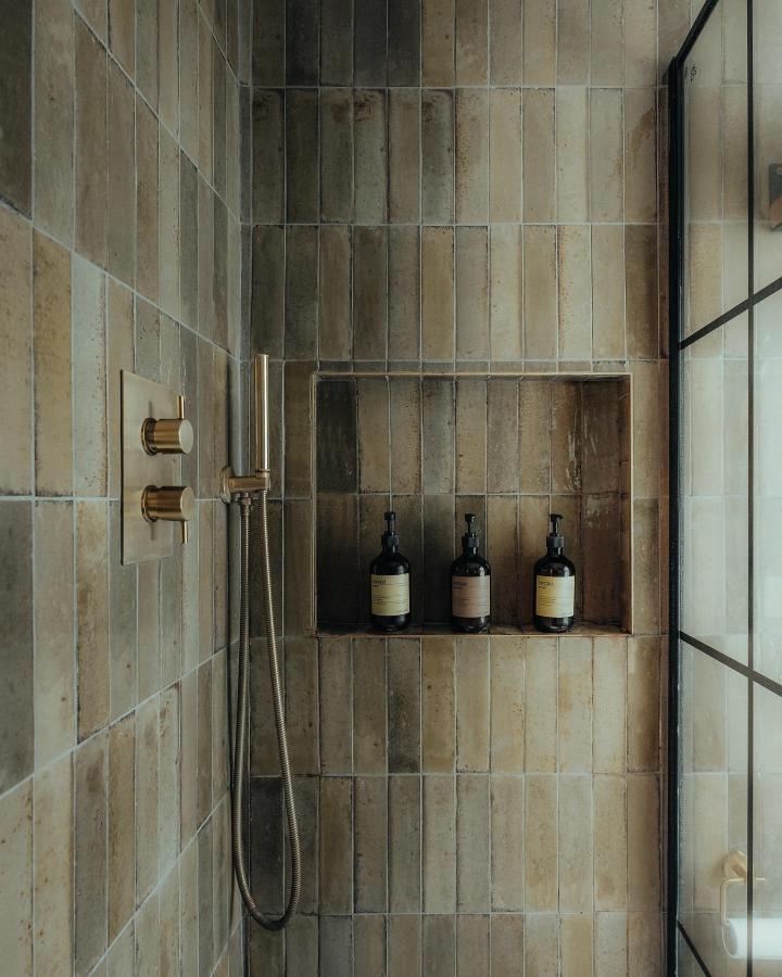Olive green handmade effect tiles with brass fixtures in shower niche from @insideourmoodyhome. Warm earthy green bathroom decor ideas.