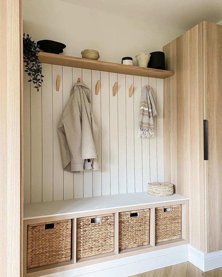 Natural woven baskets and wood hooks on a white Ikea Kallax bookshelf styling ideas from @klk.interiors. Cozy minimalist entryway storage.