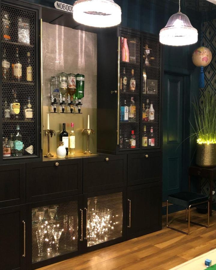 Dark painted Ikea Kallax bookshelf styling ideas with wire mesh doors and brass hardware as a home bar by @the.place.next.door.