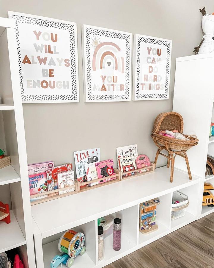White Ikea Kallax shelves styled with wooden book holders and pastel prints from @theosbornfour for ikea kallax bookshelf styling ideas in a kids room