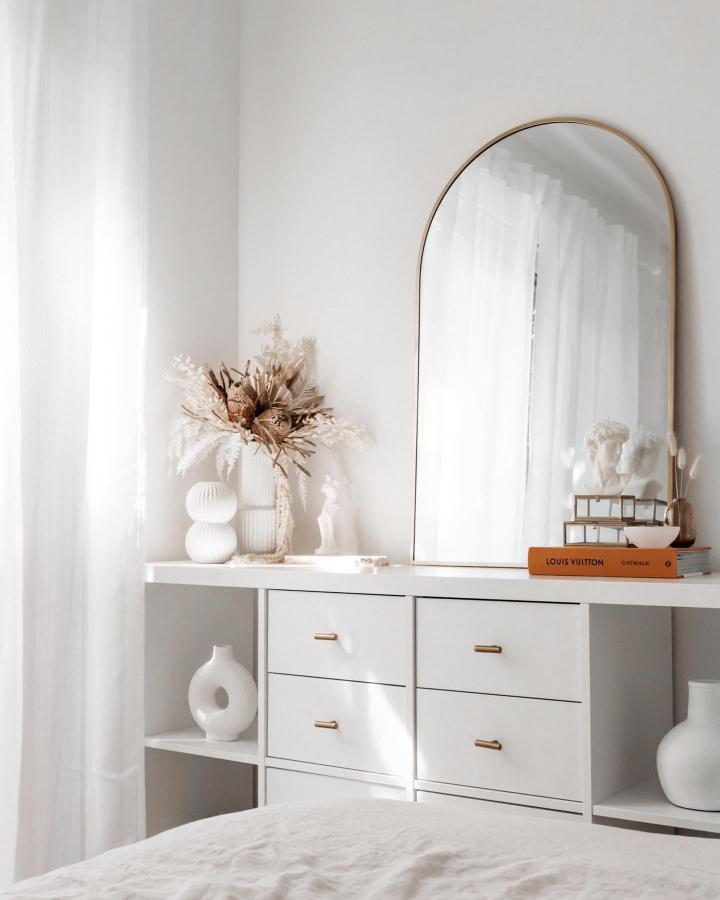 White Ikea Kallax bookshelf styled with gold handles, dried florals, ceramics, and a tall mirror from @_ashlee_white_ creating airy bedroom decor ikea kallax bookshelf styling ideas.