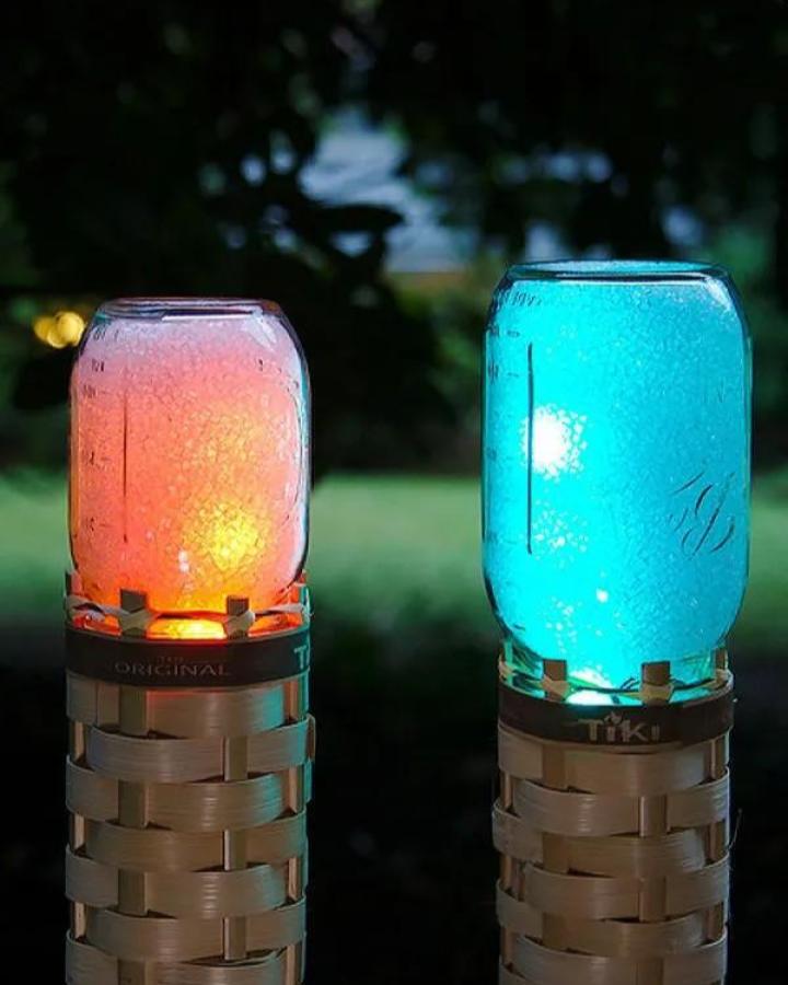 Frosted glass Mason jar crafts for adults glowing with colorful LED lights in bamboo tiki torch holders from Adafruit. Outdoor luminous craft idea.