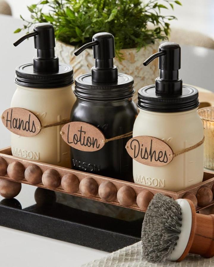 Cream and black painted mason jar soap dispensers with twine tags and a wooden tray from @hobbylobby. Organized rustic charm for mason jar crafts for adults.
