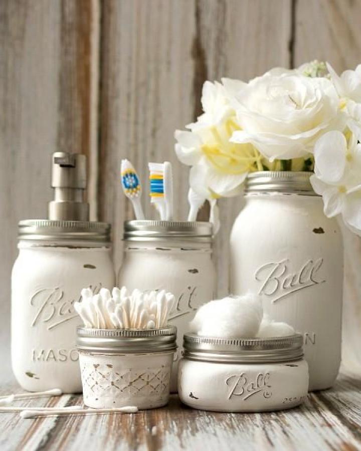 Whitewashed rustic Mason jar bathroom storage jars from Mason Jar Crafts Love with distressed paint and metal lids for organizing cotton swabs and flowers