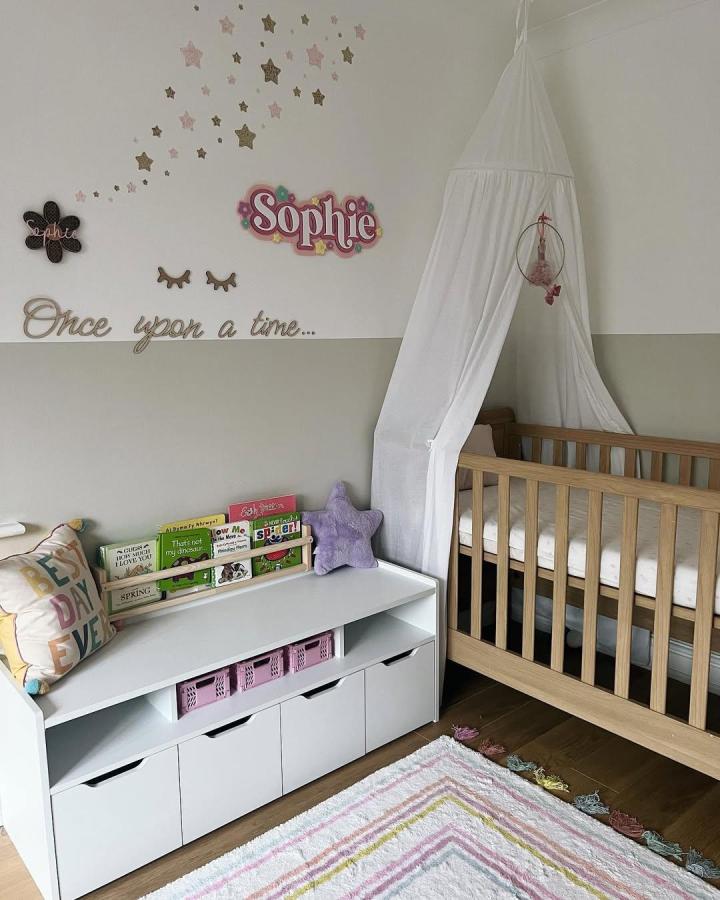 natural wood crib and white storage bench ikea nursery storage ideas from @blooms_abode with cozy pastel decorations and star-themed wall decals