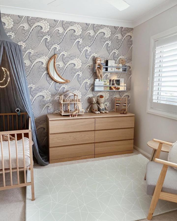 Light oak dresser and gray floating shelves in a serene nursery by @mama__wise featuring ikea nursery storage ideas. Simple and elegant.