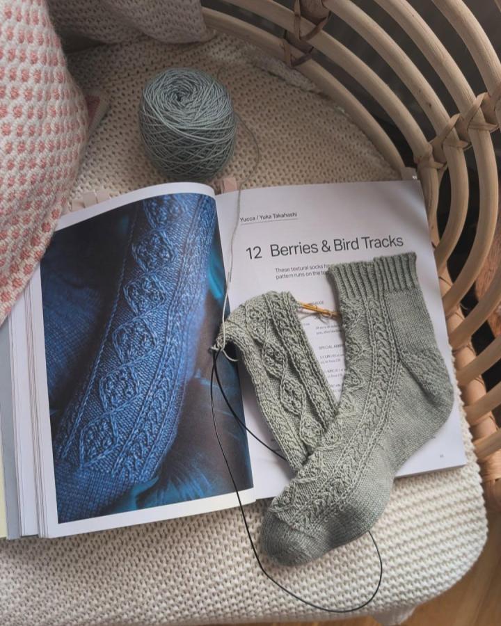 sage green textured knit socks on cream cushion from @_handmade_by_emily featuring mindful crafts for beginners knitting project with berry and bird track pattern