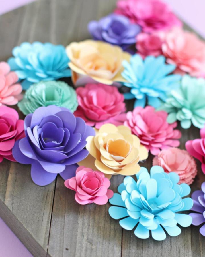 Bright pastel rolled paper flowers arranged on wooden surface from The Craft Patch. Colorful layered petals perfect for paper crafts for adults.
