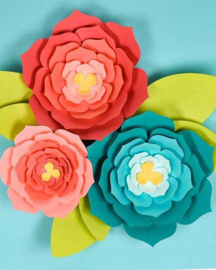 Bright layered paper flowers with green leaves from Hey Let's Make Stuff. Bold, cheerful paper crafts for adults wall art design.