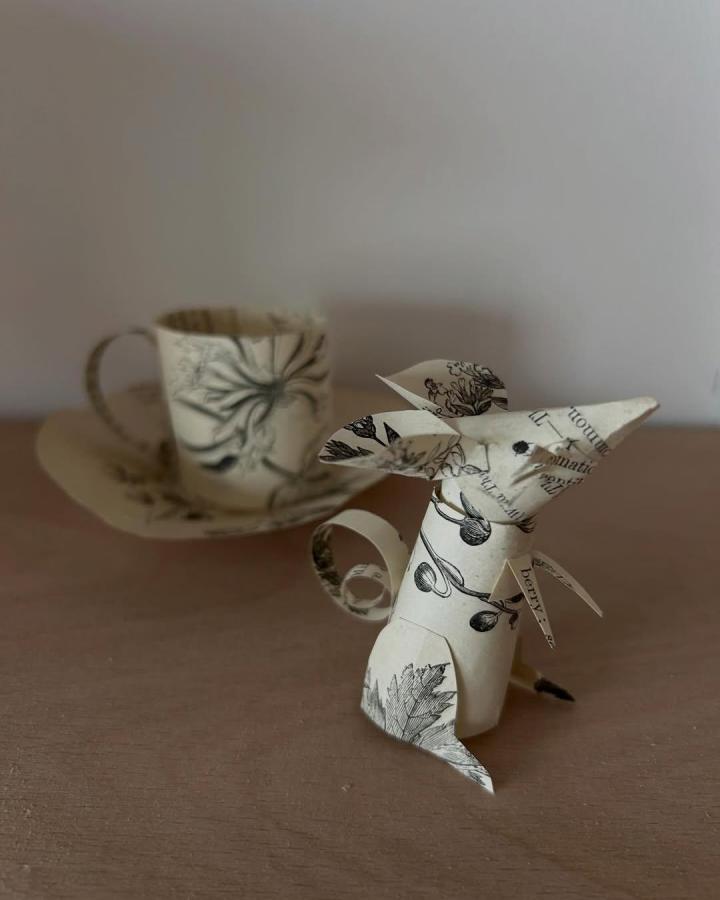 Vintage botanical print paper mouse sculpture with curled tail beside matching paper cup from @clareyoungs. Detailed nature motifs and text elements create whimsical paper crafts for adults.
