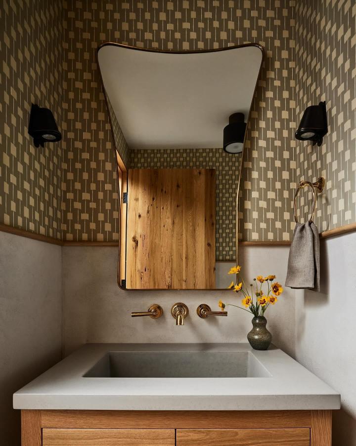Chunky olive geometric wallpaper and natural oak vanity in a small powder room from @ursinointeriors with brass fixtures and warm textures.