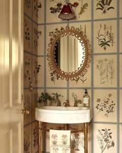 Vintage botanical grid wallpaper with brass accents in small powder room from @iksel_decorative_arts. Warm, classic, artistic nature-inspired design.