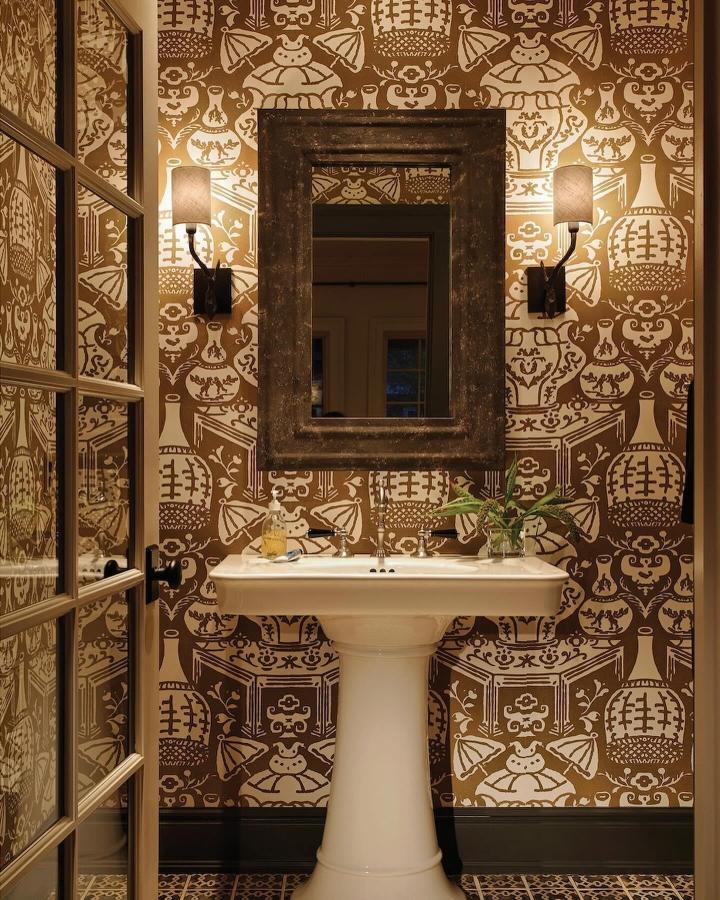 Brown and cream pottery-inspired wallpaper in a small powder room by @maisoninc with rustic mirror and pedestal sink small powder room wallpaper ideas.