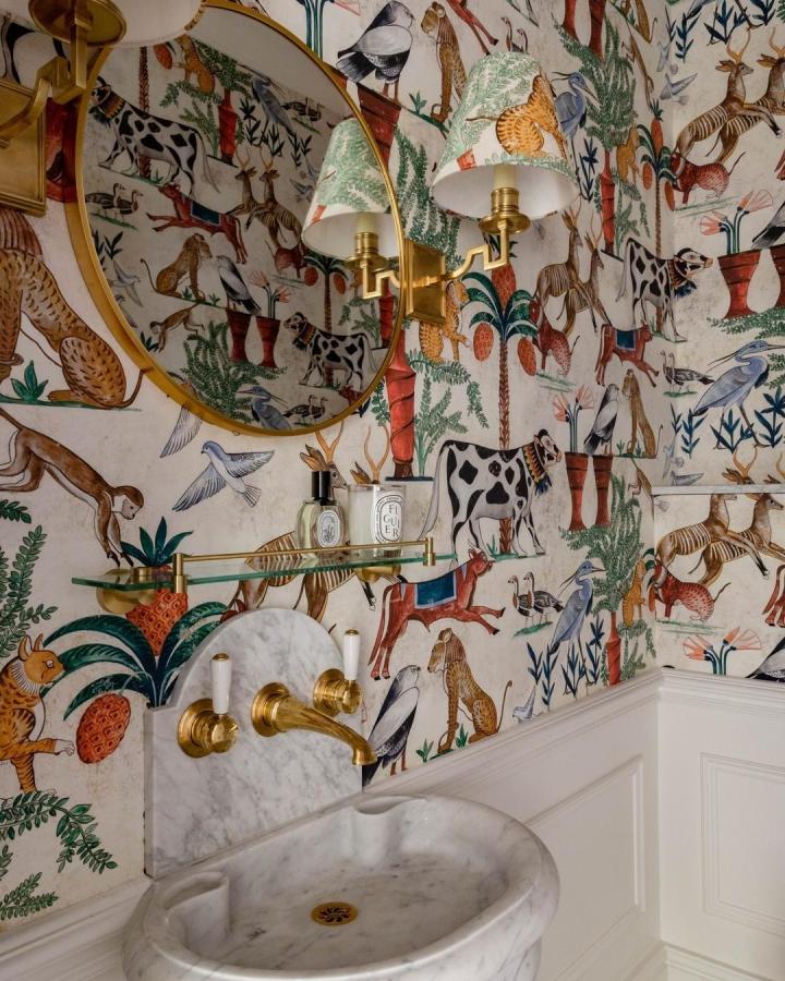Colorful animal pattern wallpaper with brass accents and marble sink in a small powder room from @blythcollinsoninteriors. Vibrant, playful small powder room wallpaper ideas.