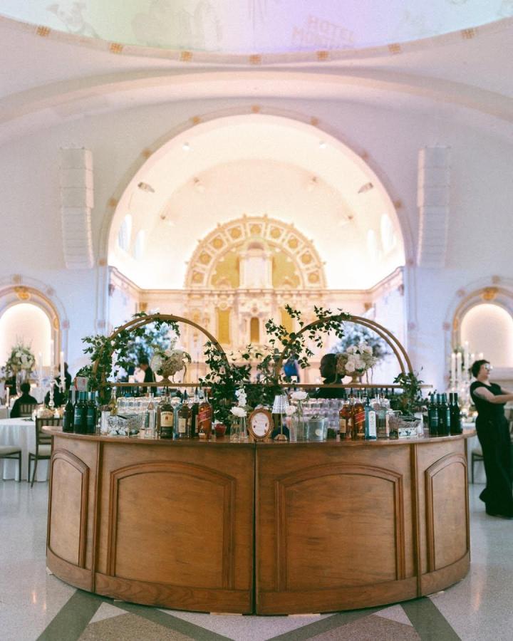 Classic wooden curved wedding bar ideas with green leafy garlands from @crystalvaseflowers. Elegant and inviting rustic setup.