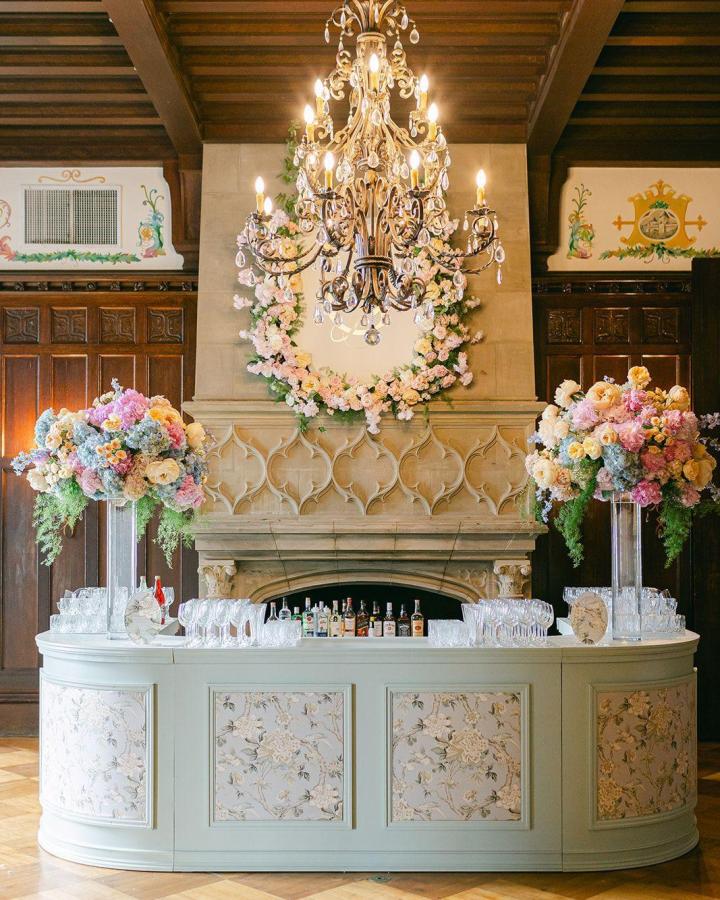 Pastel floral panels on curved elegant bar with chandelier and crystal glassware from @aboveallevents wedding bar ideas display.