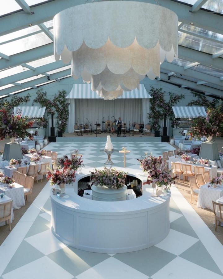 White circular wedding bar ideas with pastel floral arrangements and striped awnings from @smthingvintage in a bright reception space.