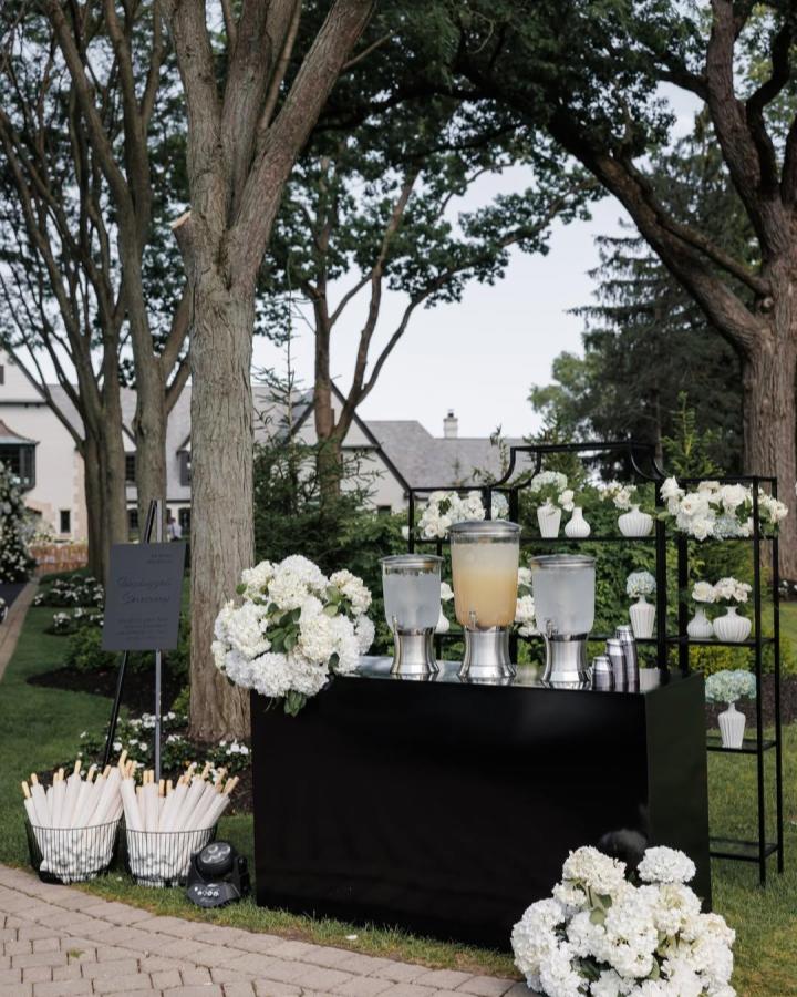 Black modern wedding bar with white hydrangea decor and silver drink dispensers from @ohdarlingdetails for wedding bar ideas outdoor setup.