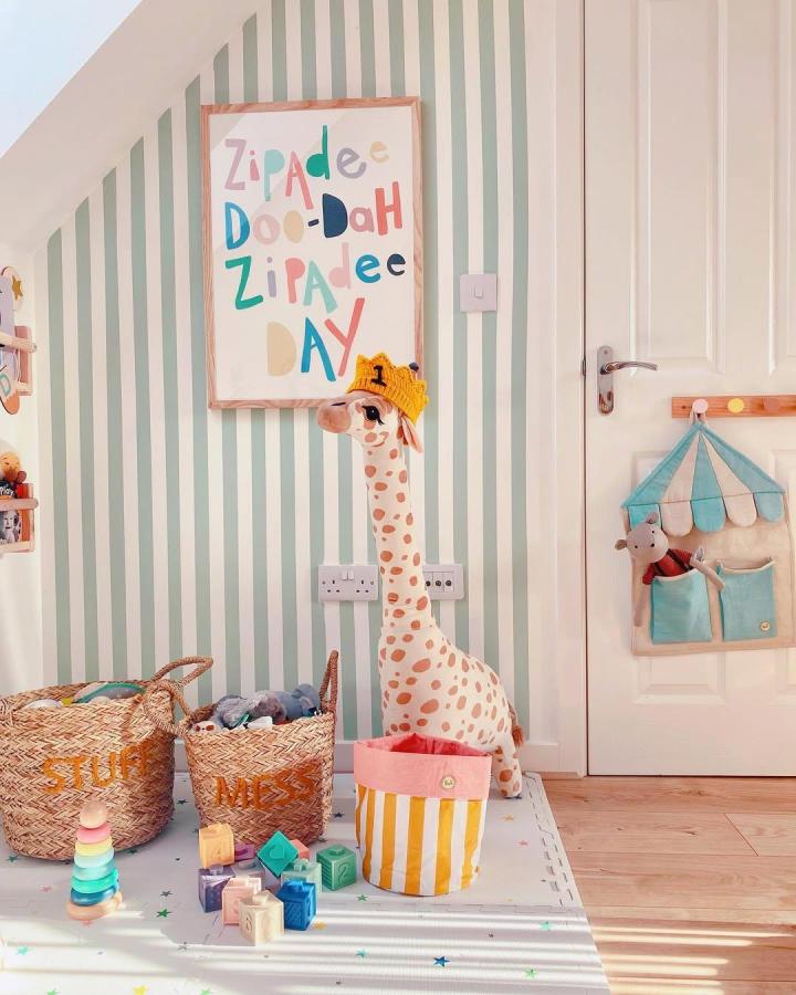 Mint and white striped nursery with woven baskets and giraffe plush from @jens_den09 featuring charming circus nursery ideas and playful storage.
