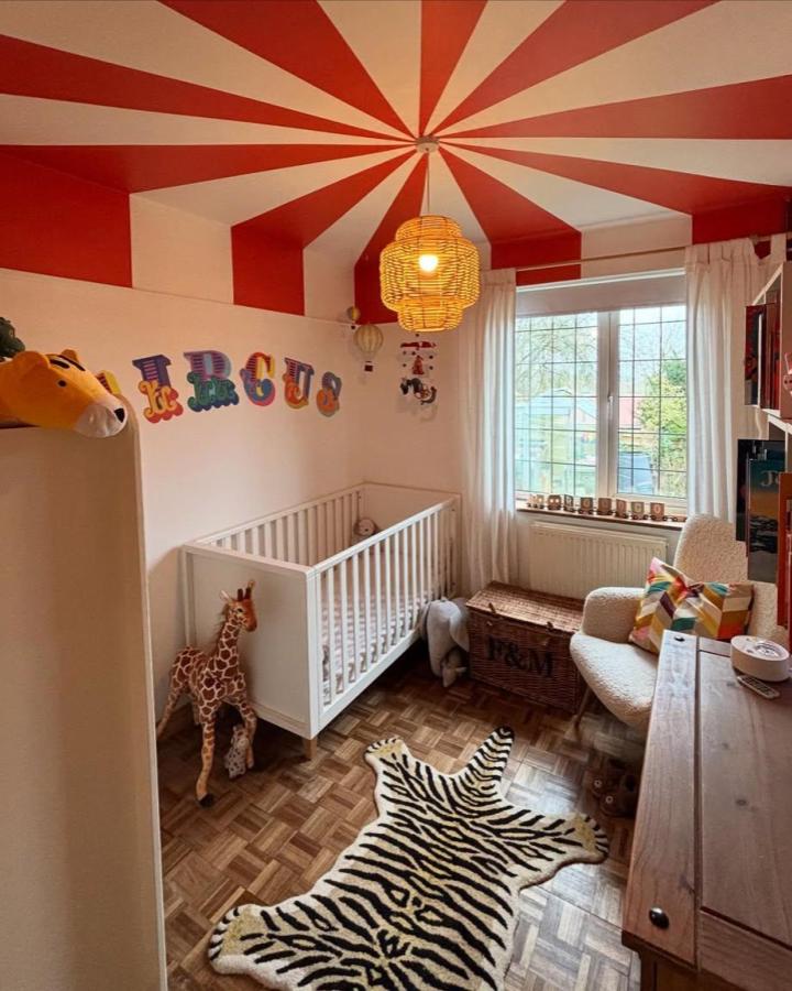 Red and white striped circus tent ceiling in nursery from @individualinteriors with zebra rug and animal toys creating circus nursery ideas.