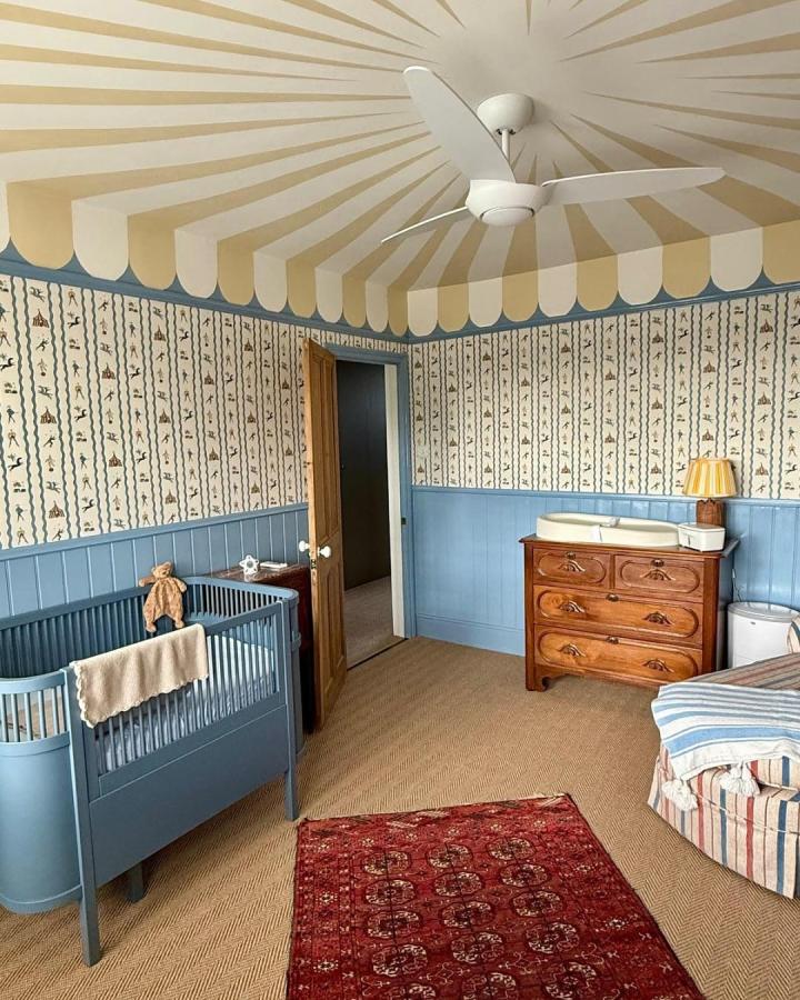 Beige and cream striped ceiling circus nursery ideas from @annikareedstudio featuring playful wallpaper and vintage wooden dresser.