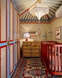 Vibrant red crib and rattan dresser with circus marquee ceiling pattern from @@opedrorusso inspired by circus nursery ideas bright and cozy space.
