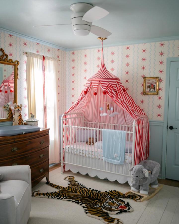 Striped red and white tent canopy in cozy nursery from @mkmcconaghy with vintage circus wallpaper and themed decor.