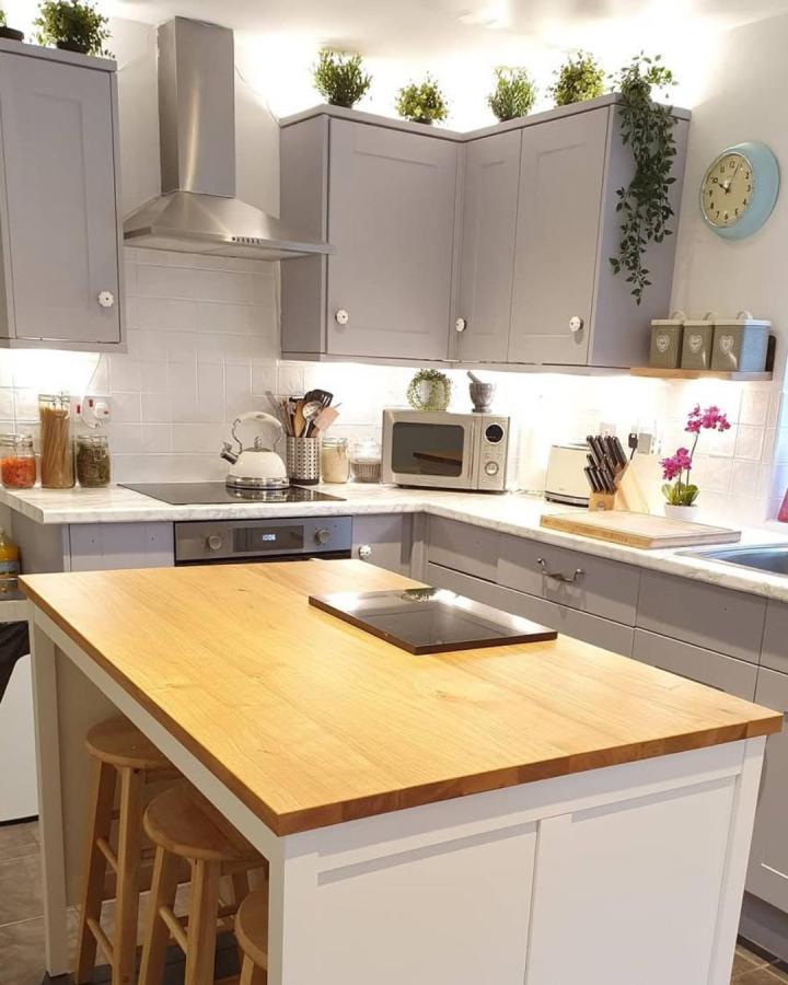 Butcher block countertop kitchen island with white base and gray cabinets from @helenbrownleyyogi. Natural wood warmth and modern minimalism combined.