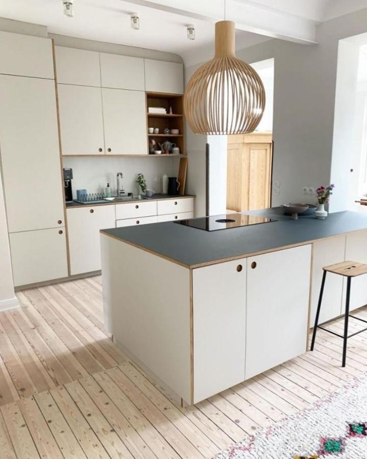 Plywood edged kitchen island with white cabinetry and dark countertop with natural wood flooring from @hej.susan Scandinavian style kitchen update.
