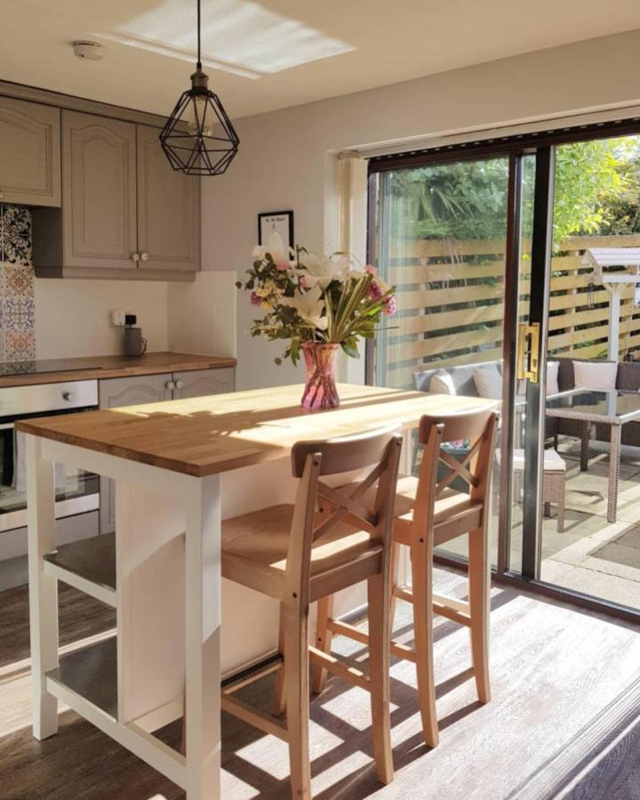 Light wood and white kitchen island with stools and flowers from @hoose_and_hame showing a clean, airy kitchen island update with storage.