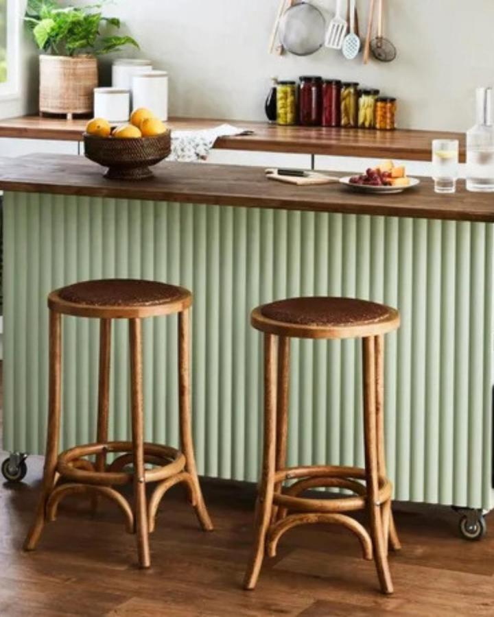 Soft green fluted front kitchen island with wood countertop and rattan stools by Kristina Soljo showcasing a stylish DIY kitchen island transformation.