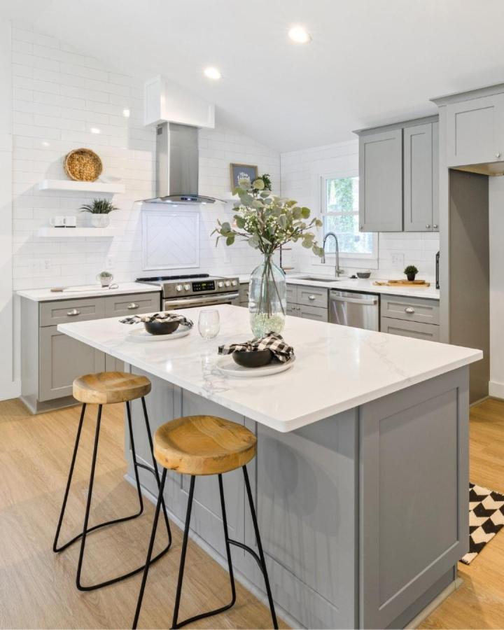 Gray kitchen island with marble-effect countertop and wooden stools by @hiiguruglobal. Contemporary design with cozy natural accents and clean lines.