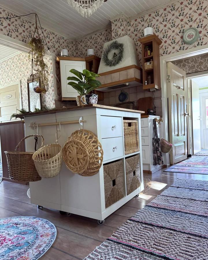 White kitchen island with woven baskets and hanging wicker baskets from @tiia.idrosenberg showing ikea kitchen island hacks with practical and stylish storage solutions.