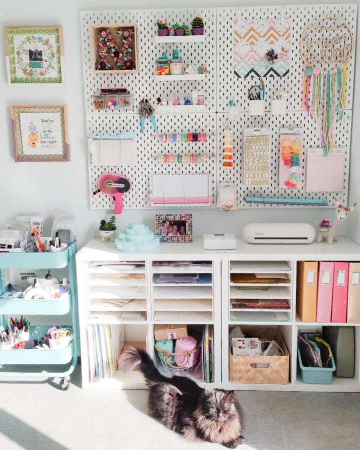 white pegboard craft wall with colorful supplies and neat storage by @sprinkles_donut ikea skadis craft room ideas bright and tidy setup sunlight on carpet with cat