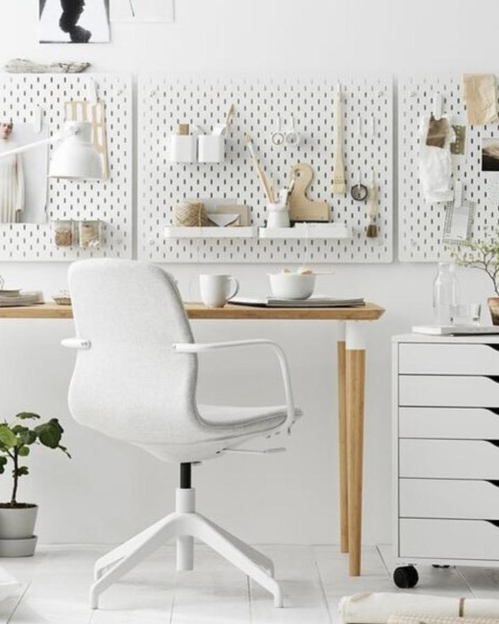 White minimalist ikea skadis craft room ideas with pegboards, wood desk, and grey swivel chair from @ikeasverige. Clean and organized workspace.