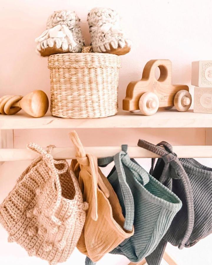 Soft pastel knit spice holders hanging on a wooden rack, cozy textured kitchen storage idea by @watchthemblossom.