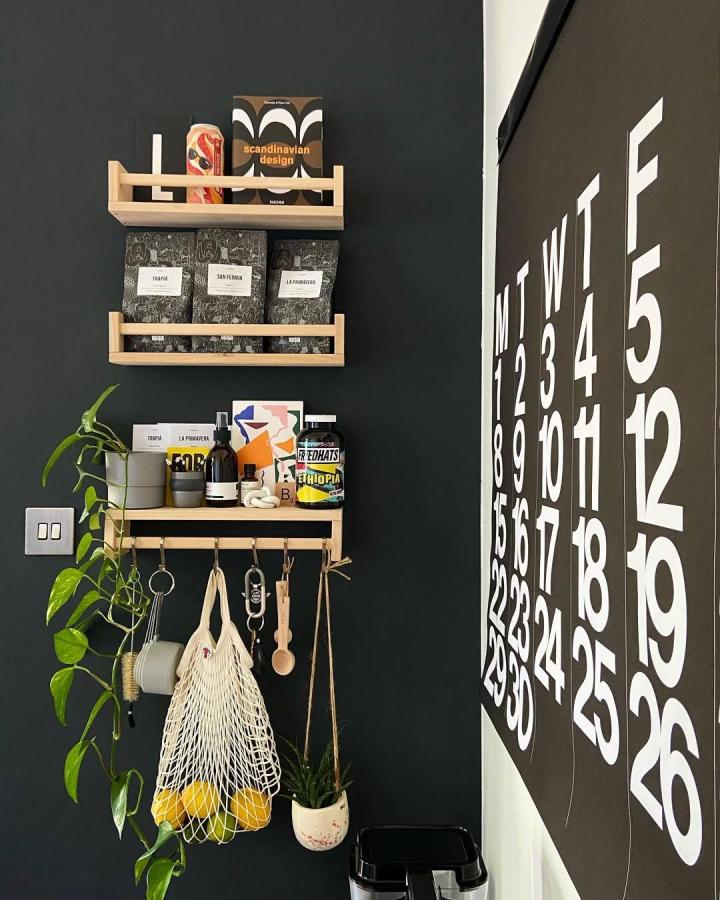Natural wood Ikea spice rack with black wall and hanging plants from @skandi.hem showcasing ikea spice rack hacks organization and style.