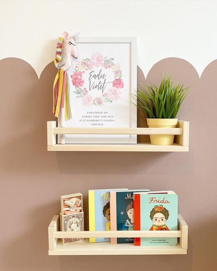 Light natural wood spice rack shelves with kids books and decor from @thehousebehindthehall in a playful styled nook. Neat and bright setup.