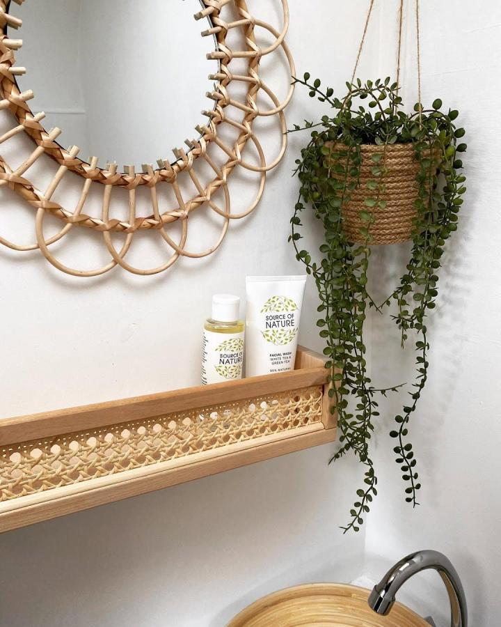 Bamboo rattan front wooden shelf with natural fiber detail and greenery from @thegoodlifevan in a bathroom setting.