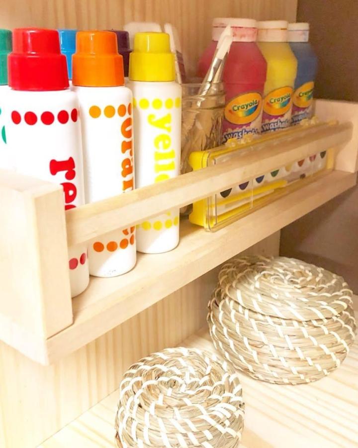 Natural wood rack holding colorful tubes and paint bottles from @organizedsanctuaries. Bright, neat, craft-inspired storage solution.
