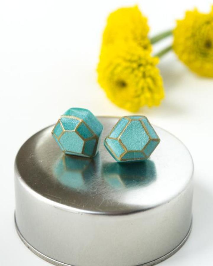 Turquoise geometric polymer clay earrings with gold edges on metal surface and yellow flowers behind design mom style.