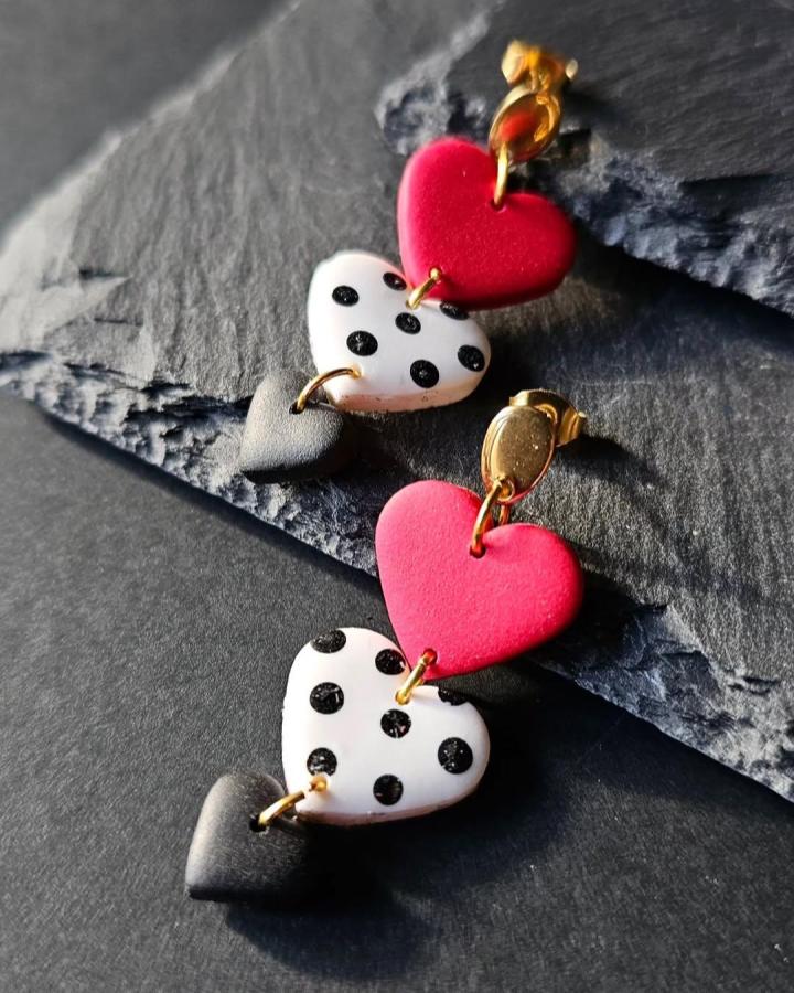 Red, white with black polka dots, and grey heart-shaped polymer clay earrings on gold studs by @vintagefloraljewel. Bright, playful layered design.