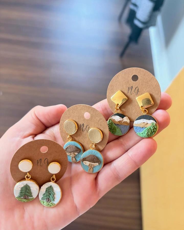 Earthy polymer clay earrings with pine, mushroom, and mountain motifs by @neutralgroundclayco, featuring gold accents and textured details.